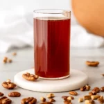 Homemade pecan syrup in a glass bottle with toasted pecans