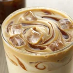 protein iced coffee in a clear glass with ice and foam
